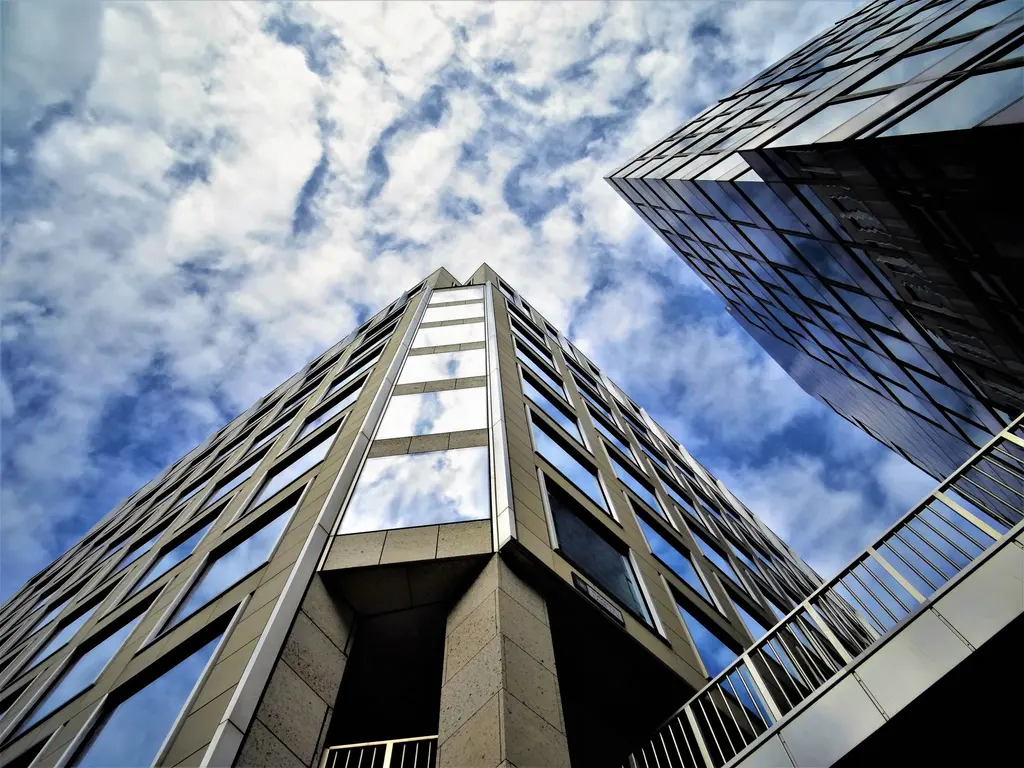 Glass office tower reflecting the sky, seen from below
